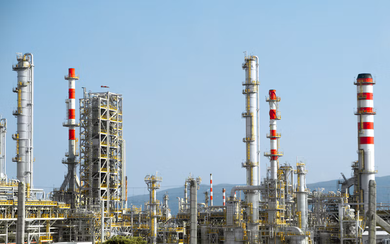 Large oil refinery with pipes, towers, and tanks under a clear blue sky